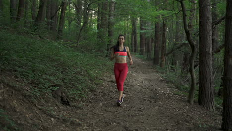 fitness woman jogging down a forest path, front view