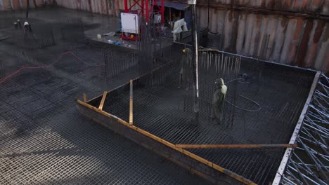 Tracking-shot-of-construction-workers-laying-cement-using-automatic-pump,-Israel