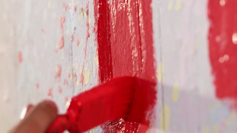 a man is painting a wall in red color with brush, close up shot, insert shot