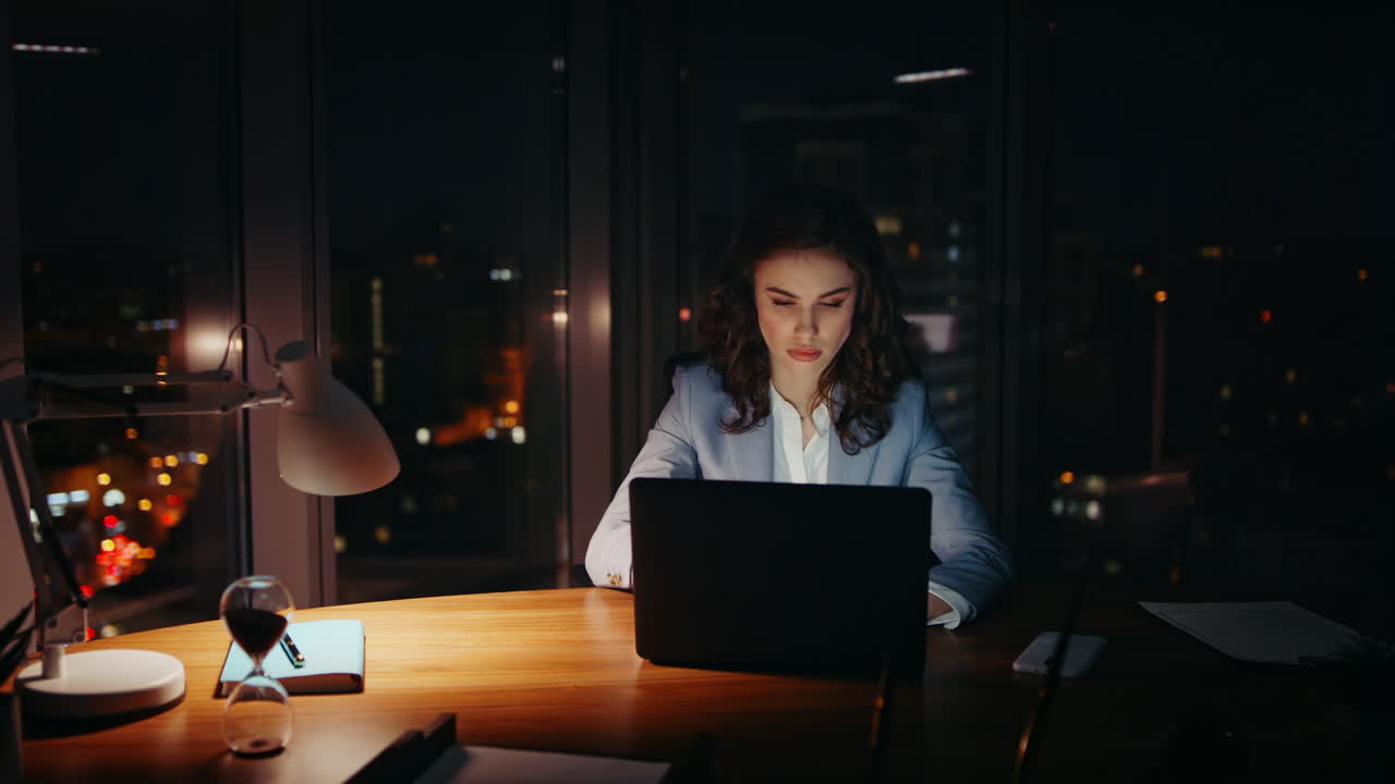 mujer sobrecargada trabajando en la oficina cerrando los ojos cansados mirando la computadora portátil por la noche.