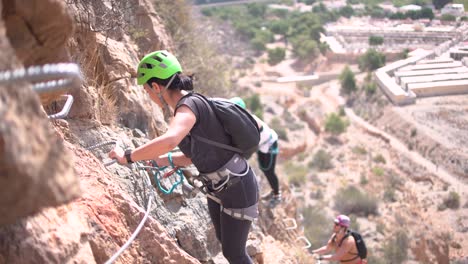 Group-of-friends-do-Via-Ferrata-climb-mountain-with-safety-equipment-in-Cartagena,-Region-of-Murcia,-Spain