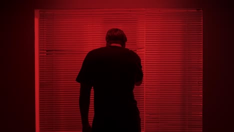 Man Looking Out of a Red Lit Window