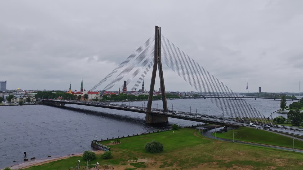 Moody drone flight draws close to Vanšu Bridge under rain and thick clouds, Riga