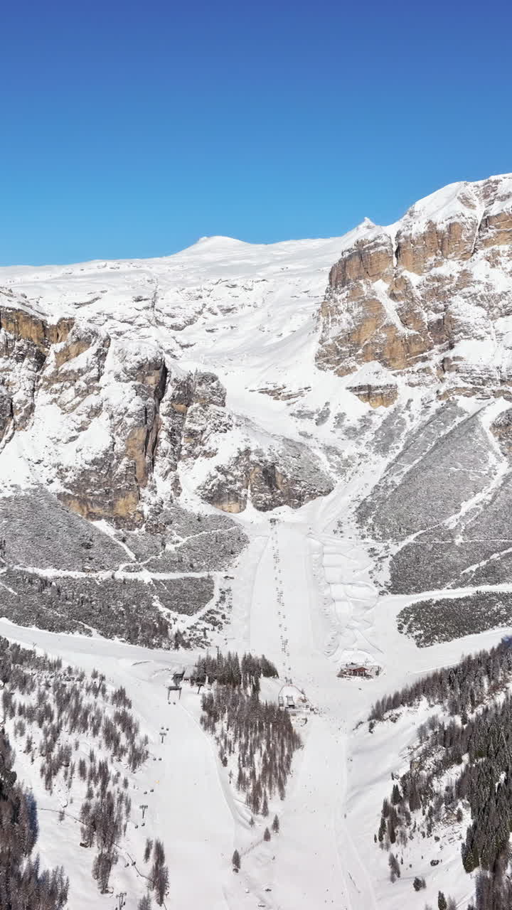 Aerial drone view of the mountains in the Colfosco village covered in snow, in South Tyrol, Dolomites, Northern Italy. Vertical