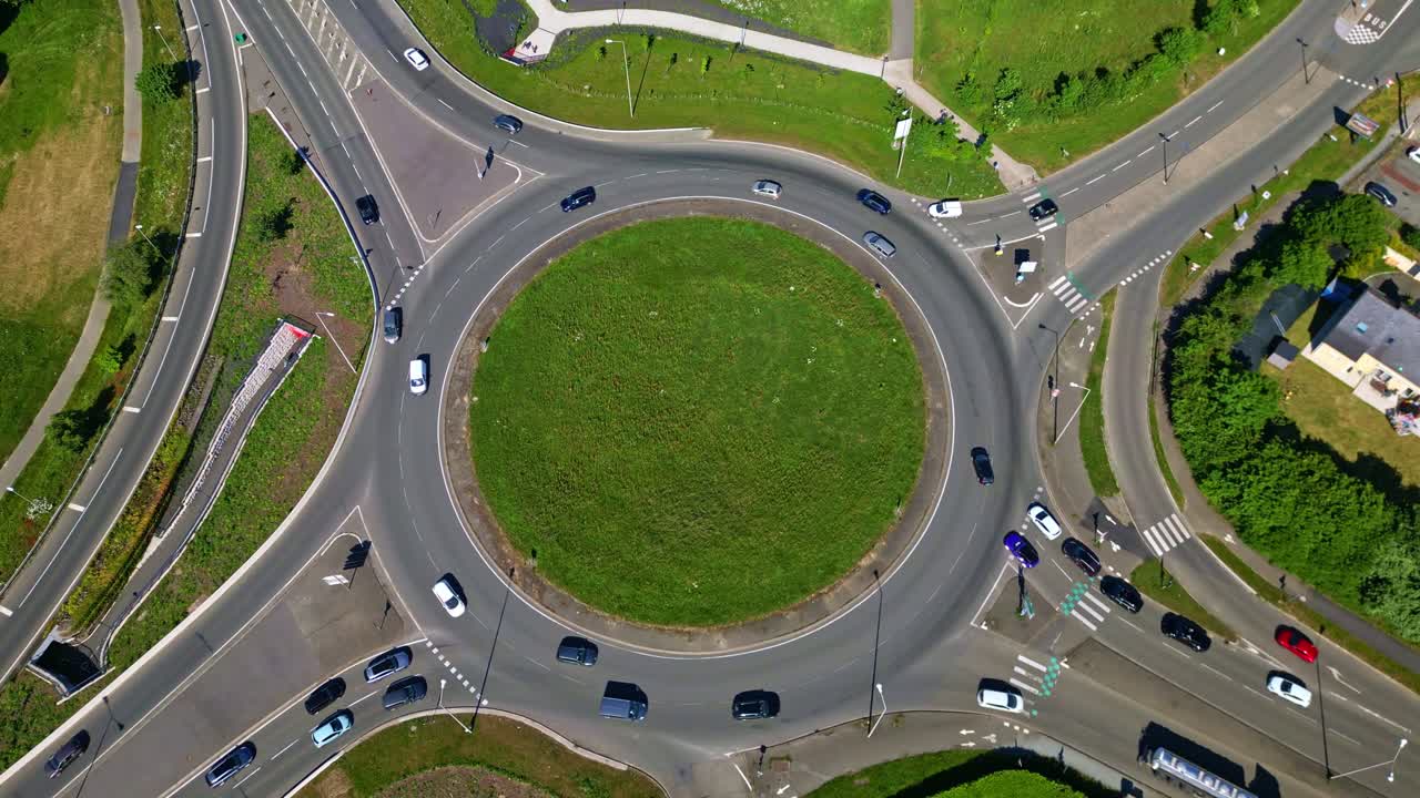 Top down drone perspective revealing circular intersection in Laval, France, showcasing vehicular movement across urban roadway during bright daylight conditions