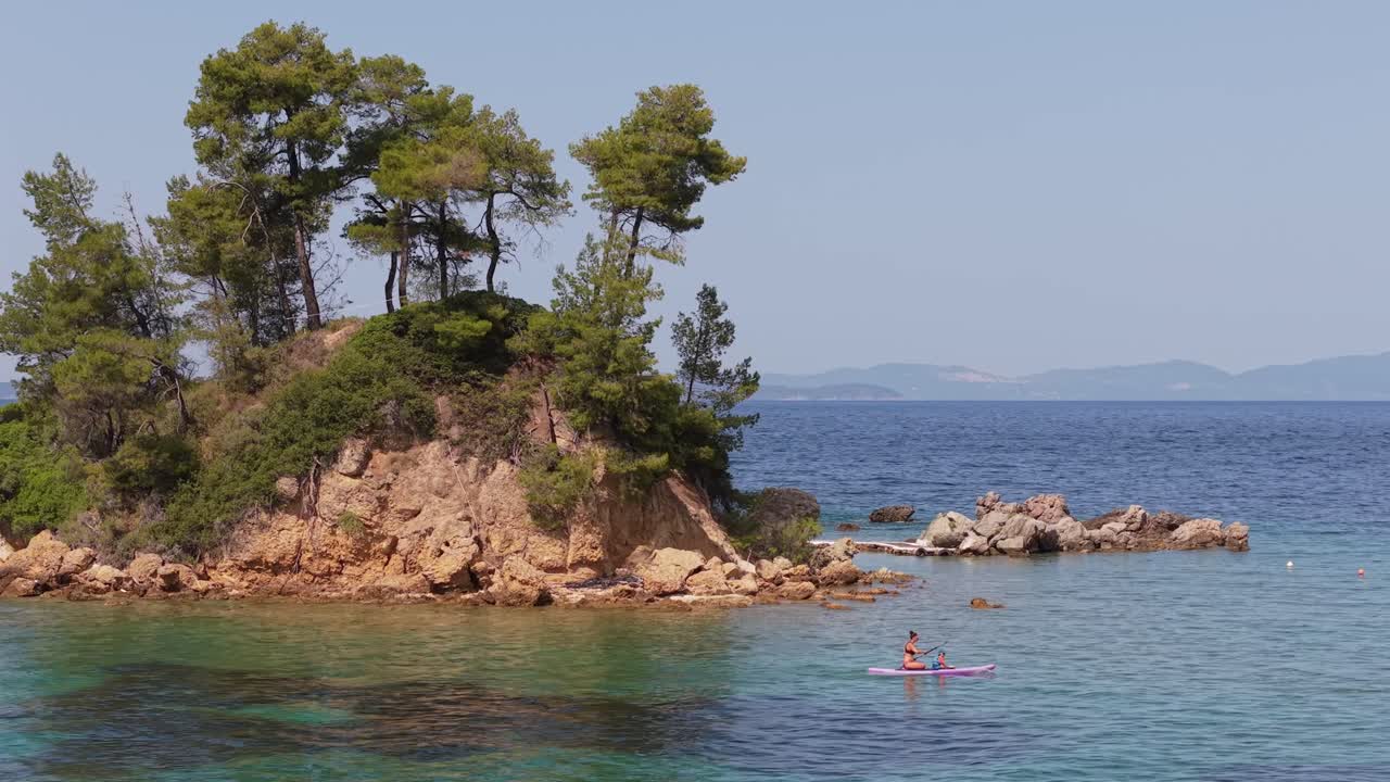 A heartwarming scene of a woman kayaking with her child, paddling peacefully near a small island surrounded by calm waters and beautiful natural scenery