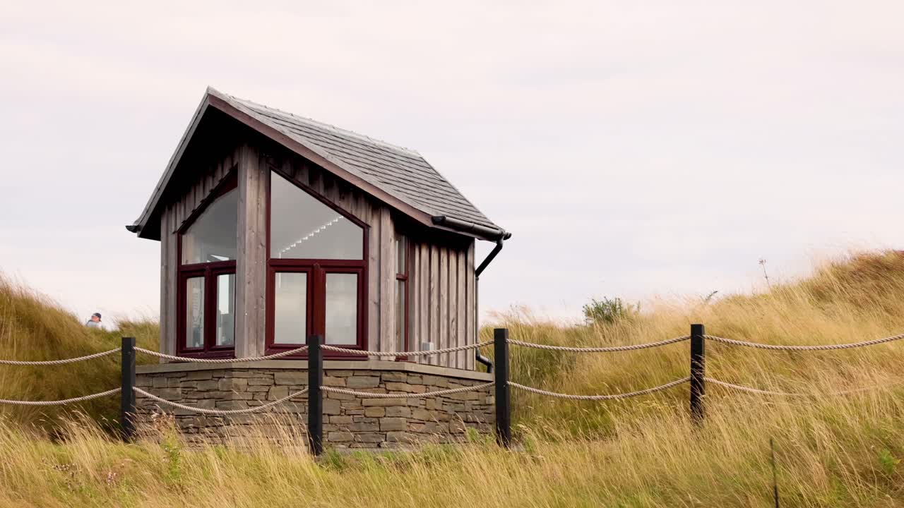 una cabaña de madera en medio de un paisaje de hierba