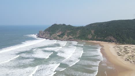drone video capturing a picturesque vietnam beach with rolling waves, golden sand, and lush greenery under clear skies, showcasing the serene coastal landscape from above