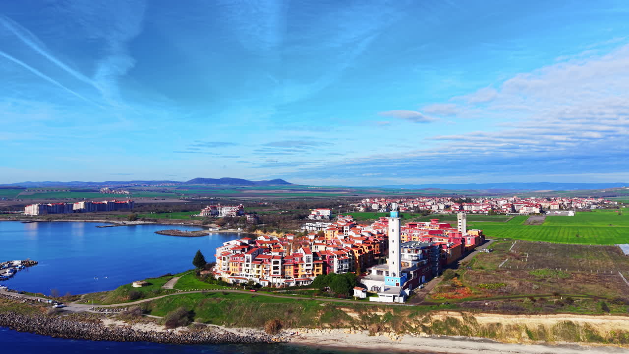 High angle panorama of a modern colorful coastal town with a lighthouse, located on a peninsula by the blue sea. Aerial view. Bulgaria