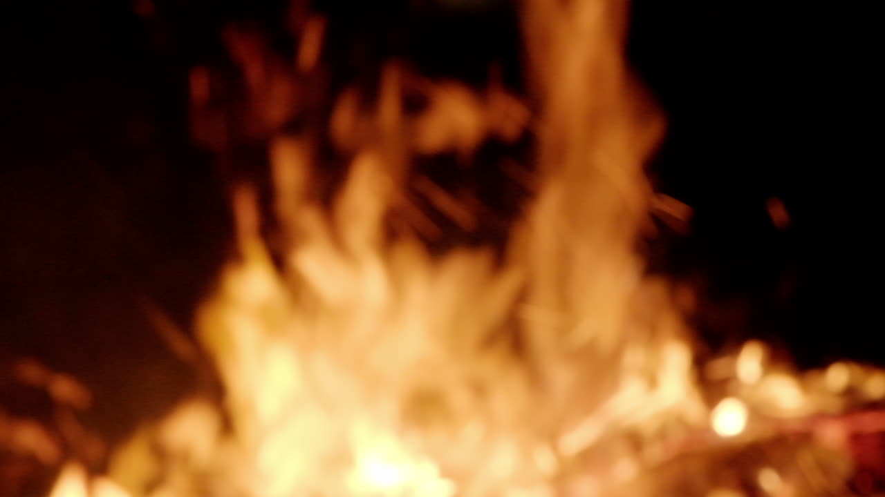 Intentional blur: fiery violent flames from a campfire burning in the tranquil darkness of the night, intense fire in slow motion