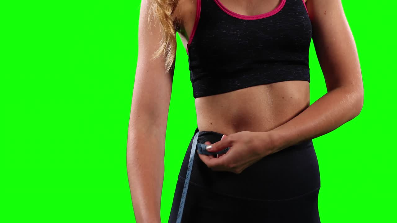 Mid section of a Caucasian active woman measuring her hips