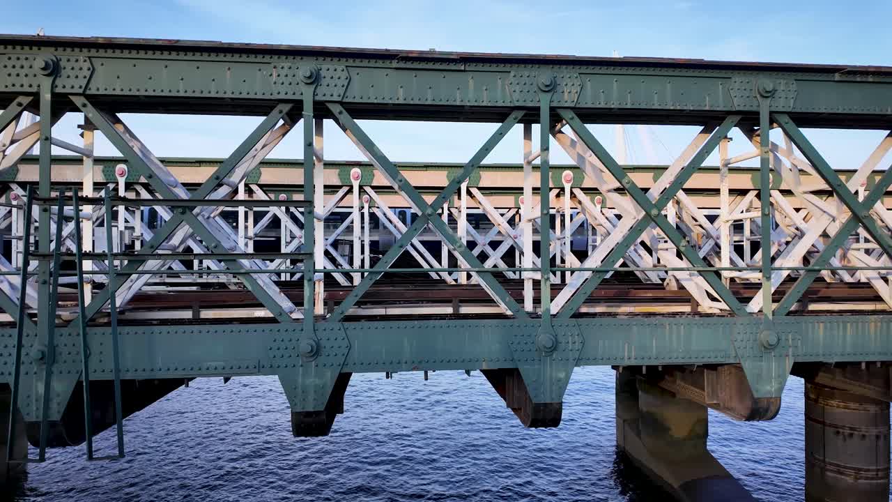 Static shot at sunset of a train crossing the Hungerford Railway Bridge, as seen from the Golden Jubilee Bridges, spanning the River Thames in London, United Kingdom