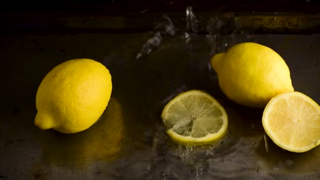 Grupo-De-Limones-Enteros-Con-Rodajas-Caídas-Desde-Arriba-Y-Salpicadas-De-Agua-En-Un-Ambiente-Oscuro