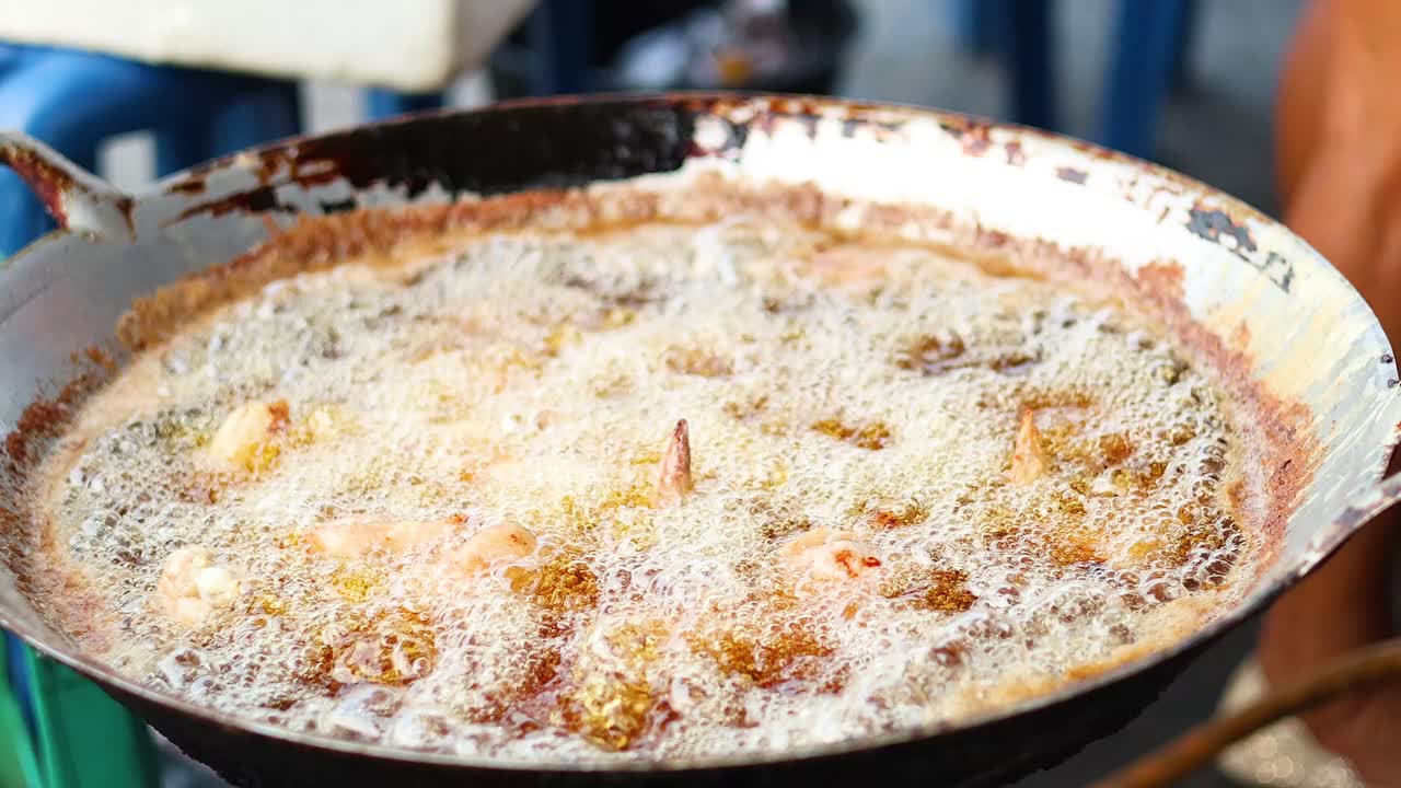 pollo frito en aceite caliente en el puesto de comida callejera
