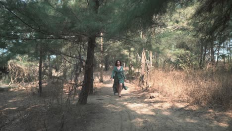 Cinematic-video-of-fashion-model-slowly-walking-through-the-forest-down-sandy-track-towards-camera