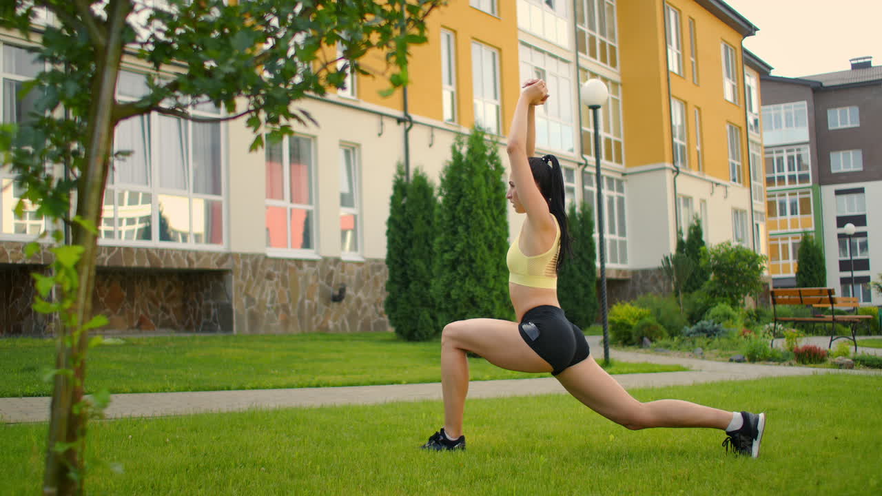 una mujer en el parque hace yoga en el parque en la hierba verde con auriculares