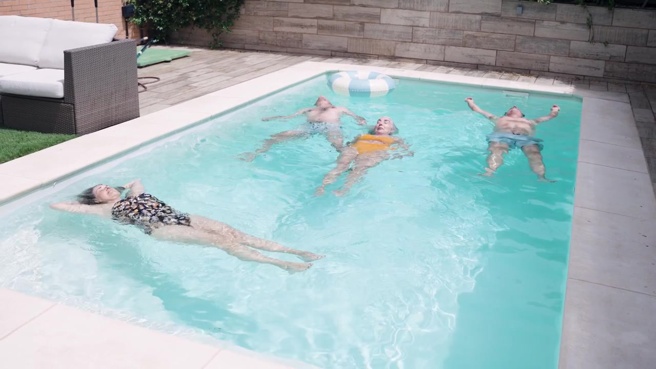 Group of Friends Floating Relaxed in a Backyard Swimming Pool