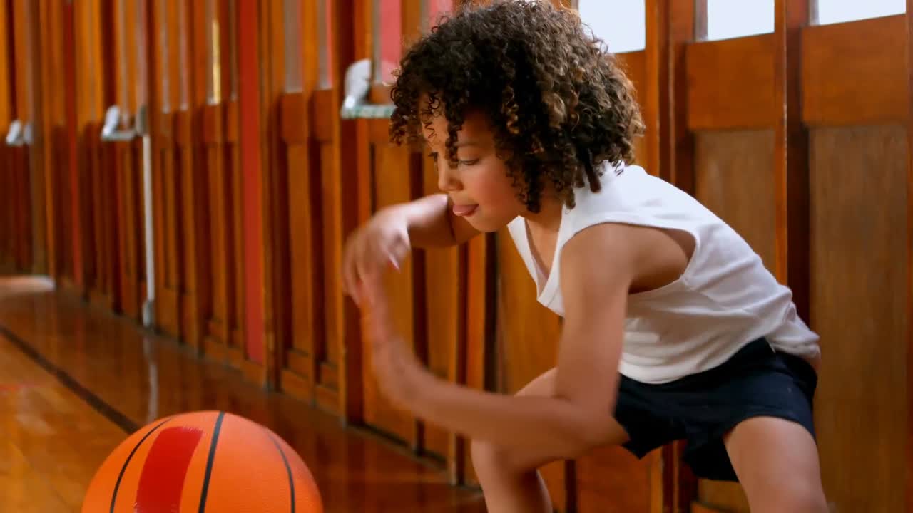 Atletisk skoledreng af blandet etnicitet spiller med basketball på skolens basketballbane 4K