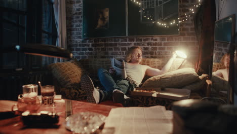 man relaxing at home with pizza and magazine