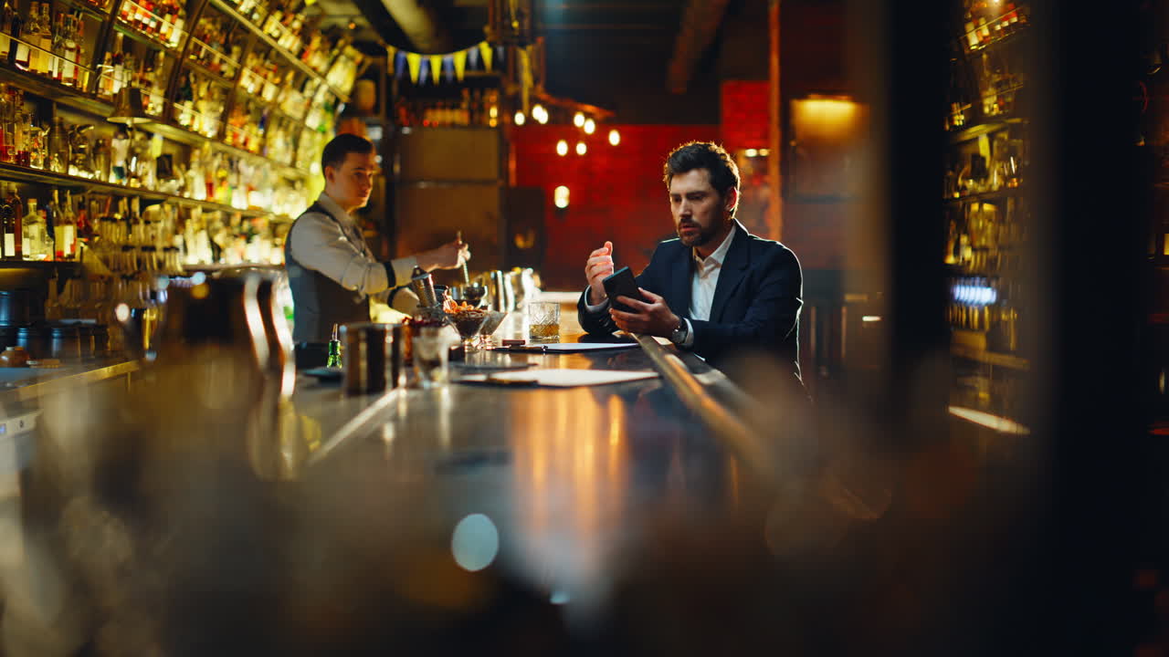 Sad guy feeling stress displeased by smartphone bad news at evening bar counter