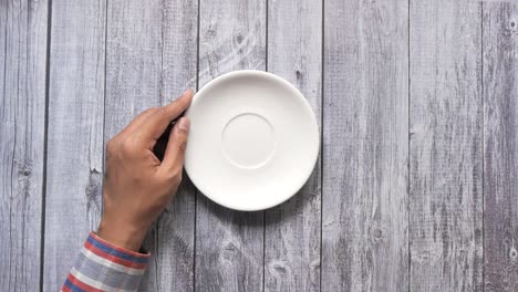 manos sosteniendo la taza de té y el plato en la mesa de madera