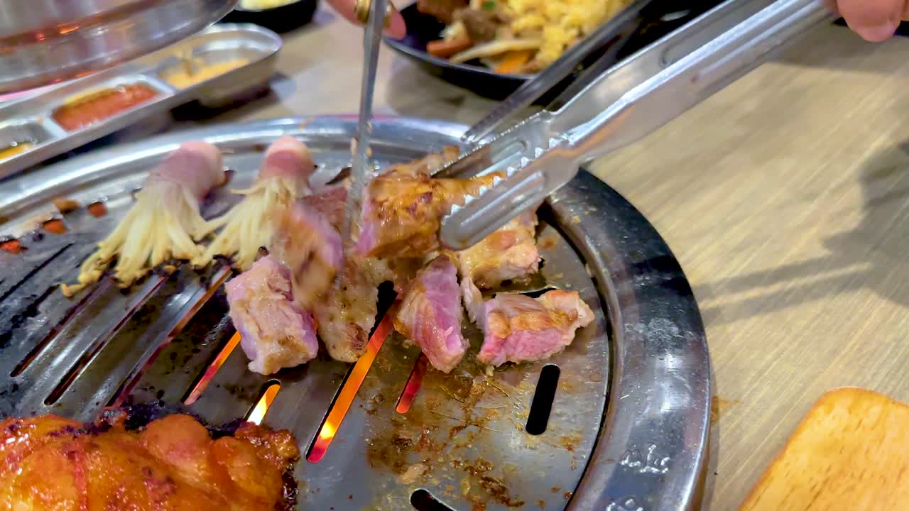 Close-up of Korean BBQ meat grilling on a tabletop grill in Bangkok, highlighting vibrant colors and dynamic cooking action