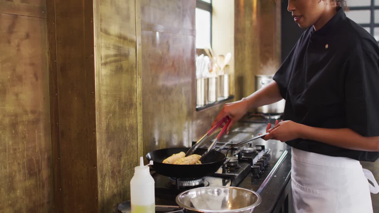 混合種族の女性シェフが料理を準備し ⁇ キッチンで微笑んでいます ⁇
