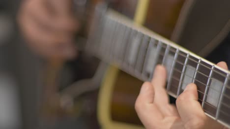 Primer-Plano-De-Un-Músico-Profesional-Tocando-Un-Solo-En-Una-Guitarra-Eléctrica-De-Cuerpo-Hueco-Con-Una-Púa-De-Guitarra-Durante-Una-Sesión-De-Grabación-En-Un-Estudio-Con-Un-Fondo-Borroso