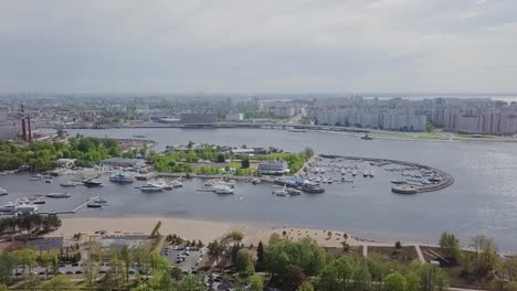 Hafenteil-Der-Stadt-Mit-Vielen-Schiffen,-Yachten,-Fabrik-Im-Hintergrund,-Stadtpanorama,-Industriepark-Und-Bäumen