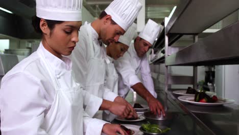 Row-of-chefs-garnishing-dessert