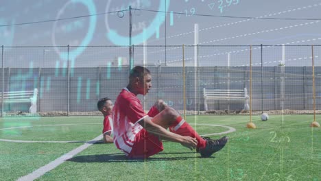 Animation-of-multiple-graphs-moving-over-multiracial-soccer-players-practicing-crunches-on-field