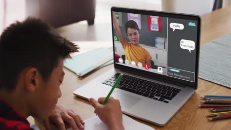 Asian-boy-doing-homework-and-having-a-video-call-with-classmate-on-laptop-at-home