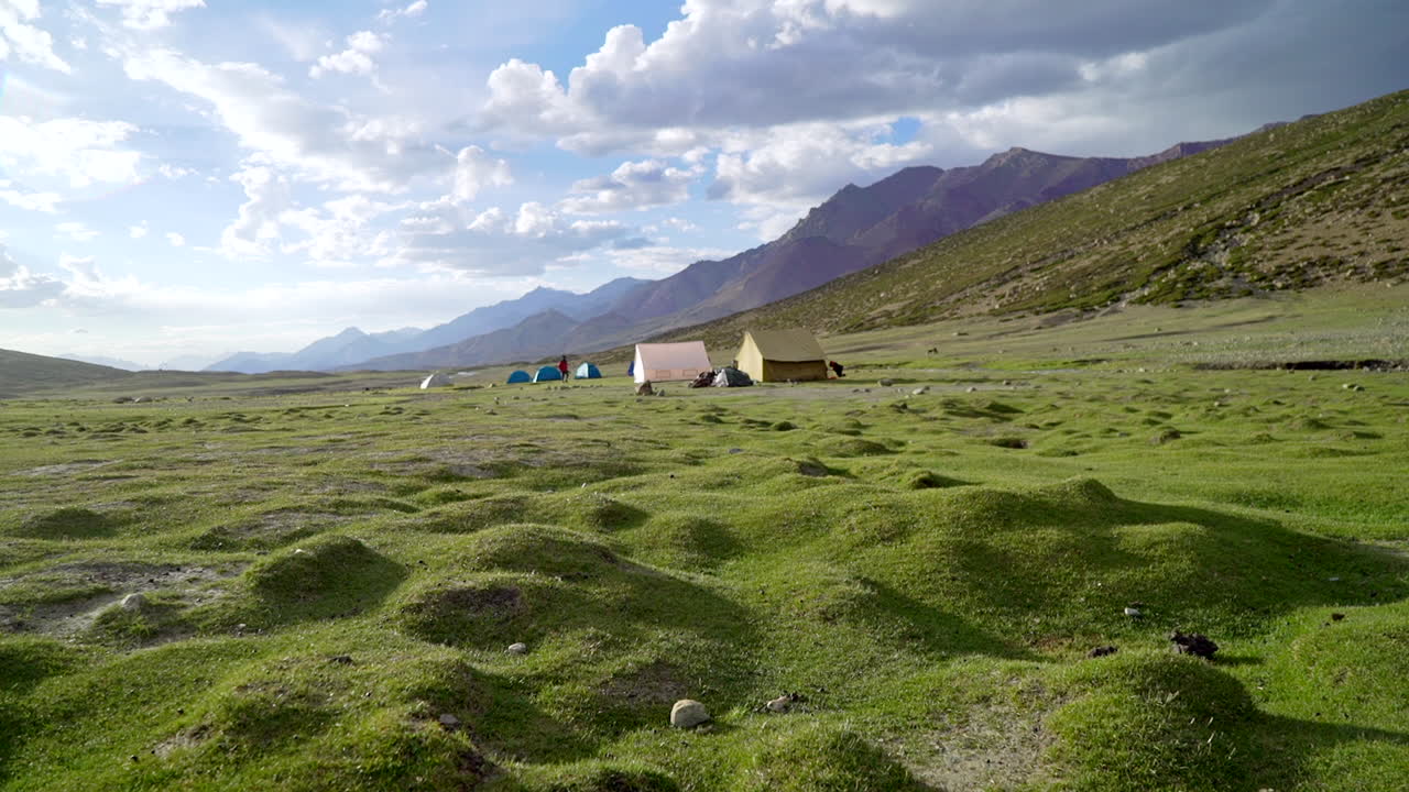 산 사이의 푸른 계곡에서 맑은 날에 텐트 사이를 걷는 등산객으로 비오는 날에 틸트 업 샷