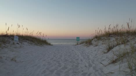 drone-flying-over-a-path-of-sea-oats-and-emerald-waters-white-sands-of-the-Gulf-of-Mexico-at-sunrise-summer-day