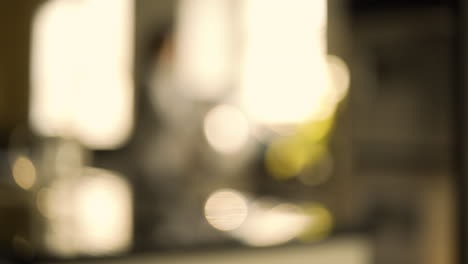 woman walks into kitchen, rack focus to soft focus and bokeh