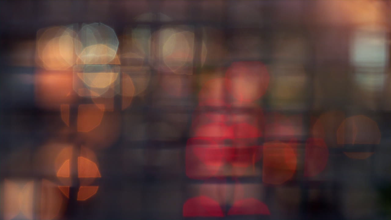 Blurred bokeh lights moving blinking at squared metallic mesh netting fence.