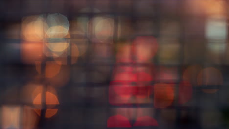 Blurred-bokeh-lights-moving-blinking-at-squared-metallic-mesh-netting-fence.