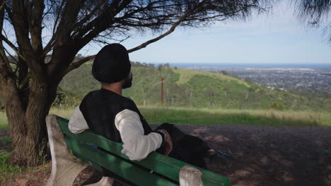 rear view of an indian sikh man sitting on a bench appreciating nature - pullback