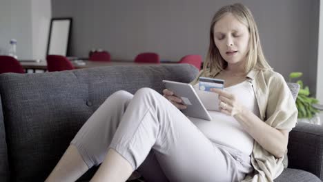 Focused-pregnant-woman-shopping-online-with-tablet