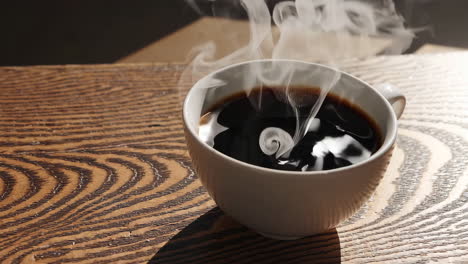 steaming hot black coffee in a white mug on a wooden table