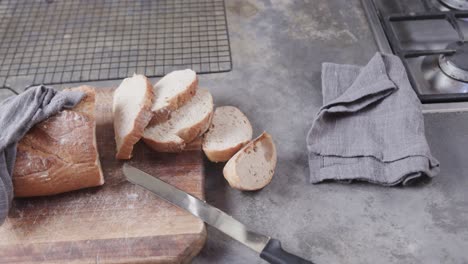 Close-up-of-sliced-bread-on-cutting-board-in-kitchen,-slow-motion