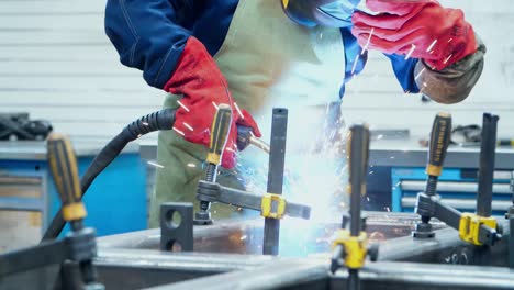 man in protective suit and mask welding metal blanks. welder in helmet