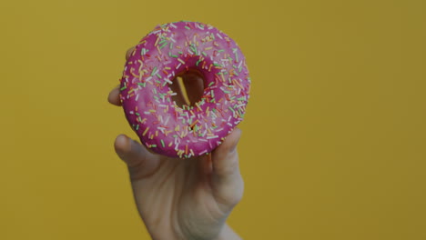 hand holding a pink glazed donut