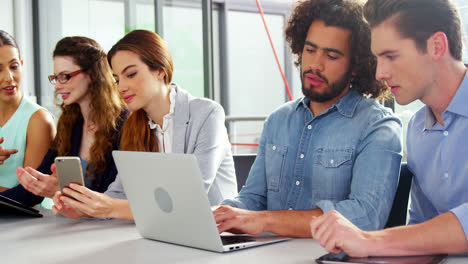 ejecutivos empresariales que utilizan portátiles, teléfonos móviles y tabletas digitales en las reuniones