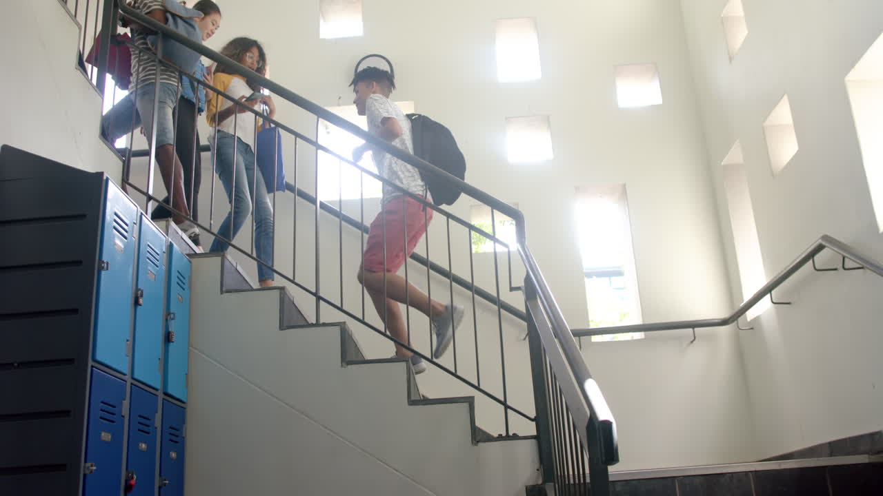 Teenagedrenge af blandet etnicitet snakker på gymnasiets trapper.