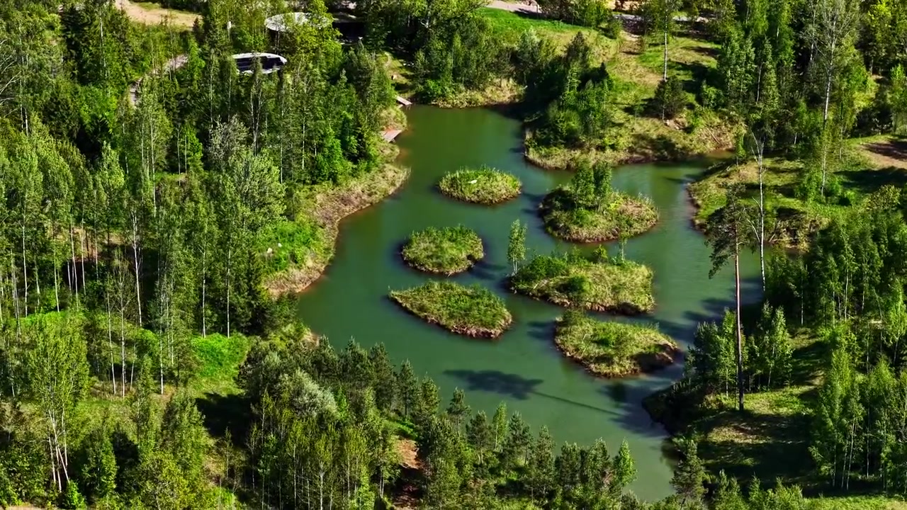 Naturskön skogssjö med flera små gröna öar och klart vatten.