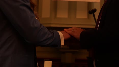 marriage officiant holding hands of couple during wedding ceremony