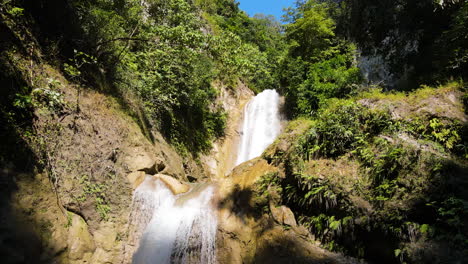 flying towards the waterfalls in the forest on a sunny day in summer in sumba island, indonesia