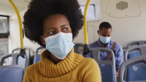 african american businesswoman with face mask sitting in bus
