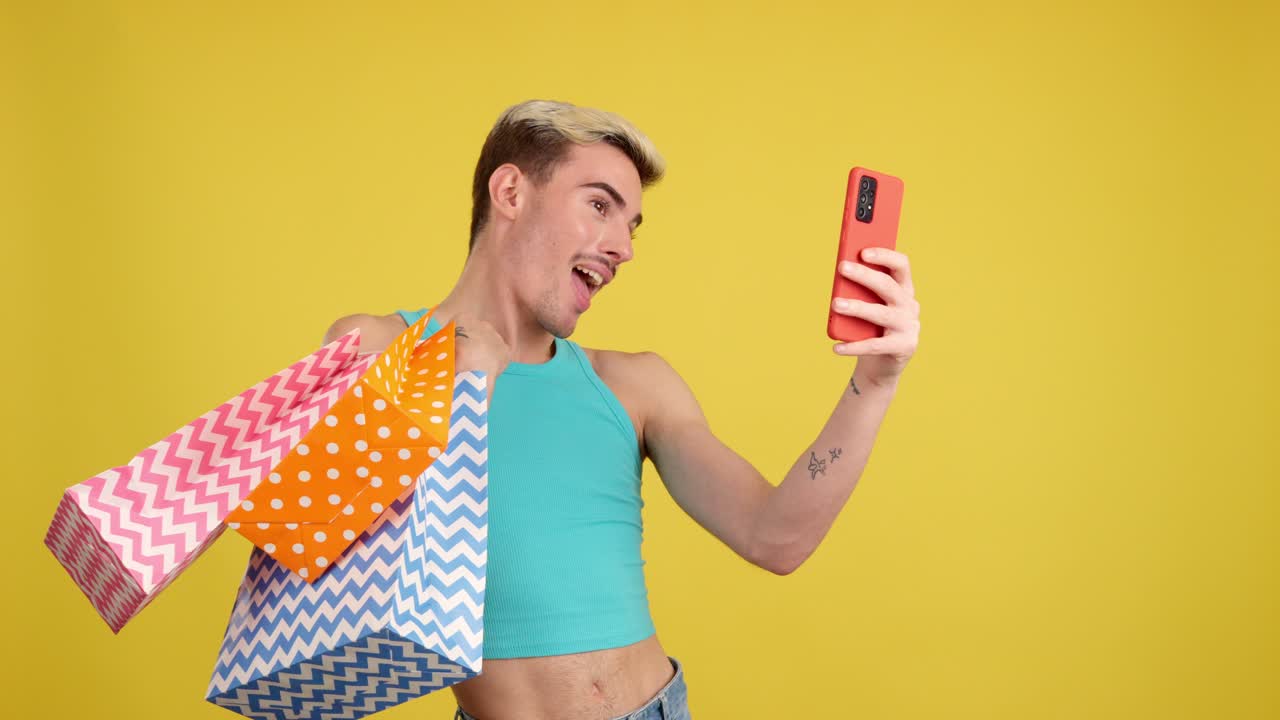 Man with shopping bags using phone on yellow background